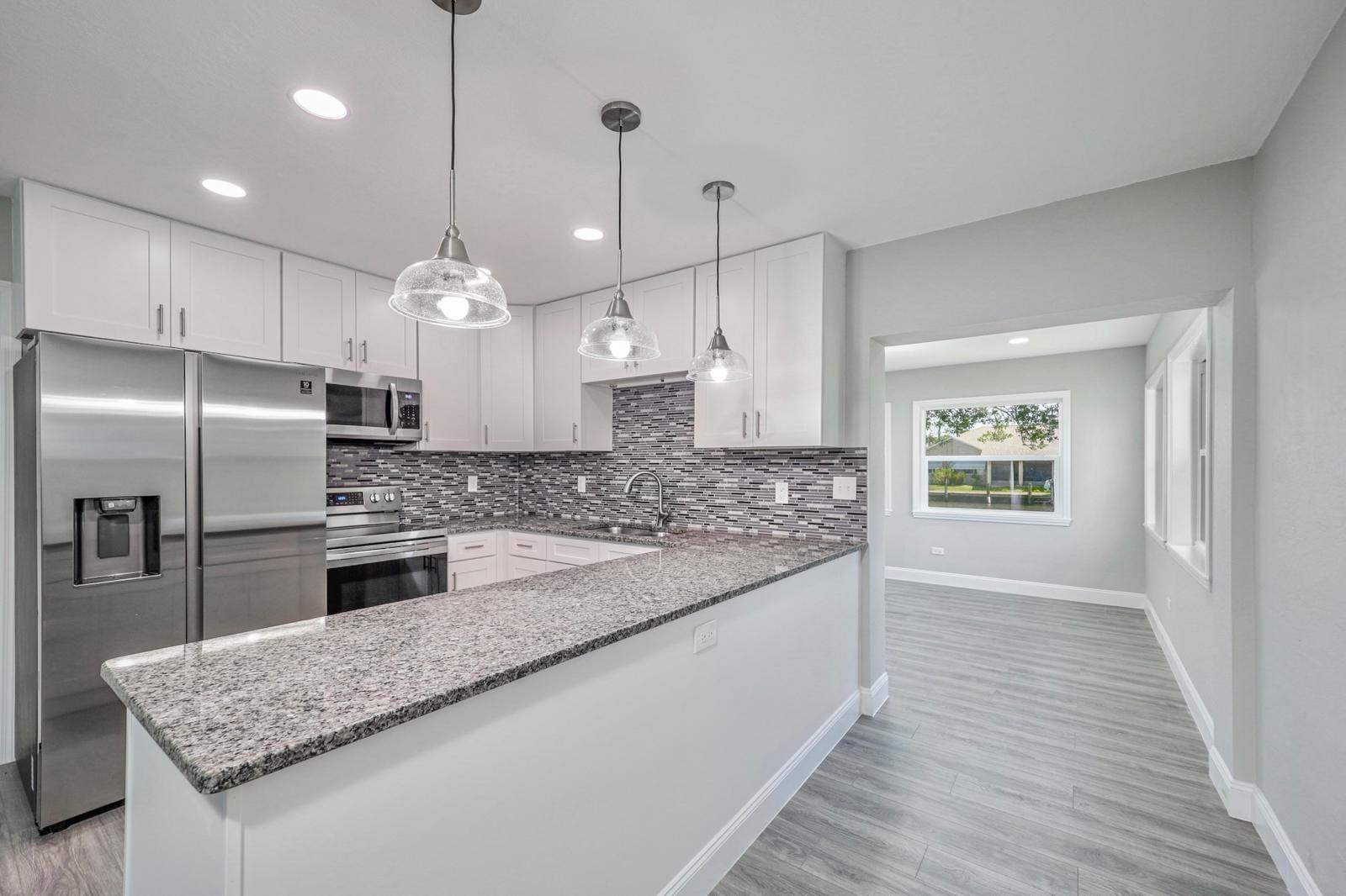 Bright white kitchen with granite island and pendant lights — The Bayfront Residence, Palm Coast, FL