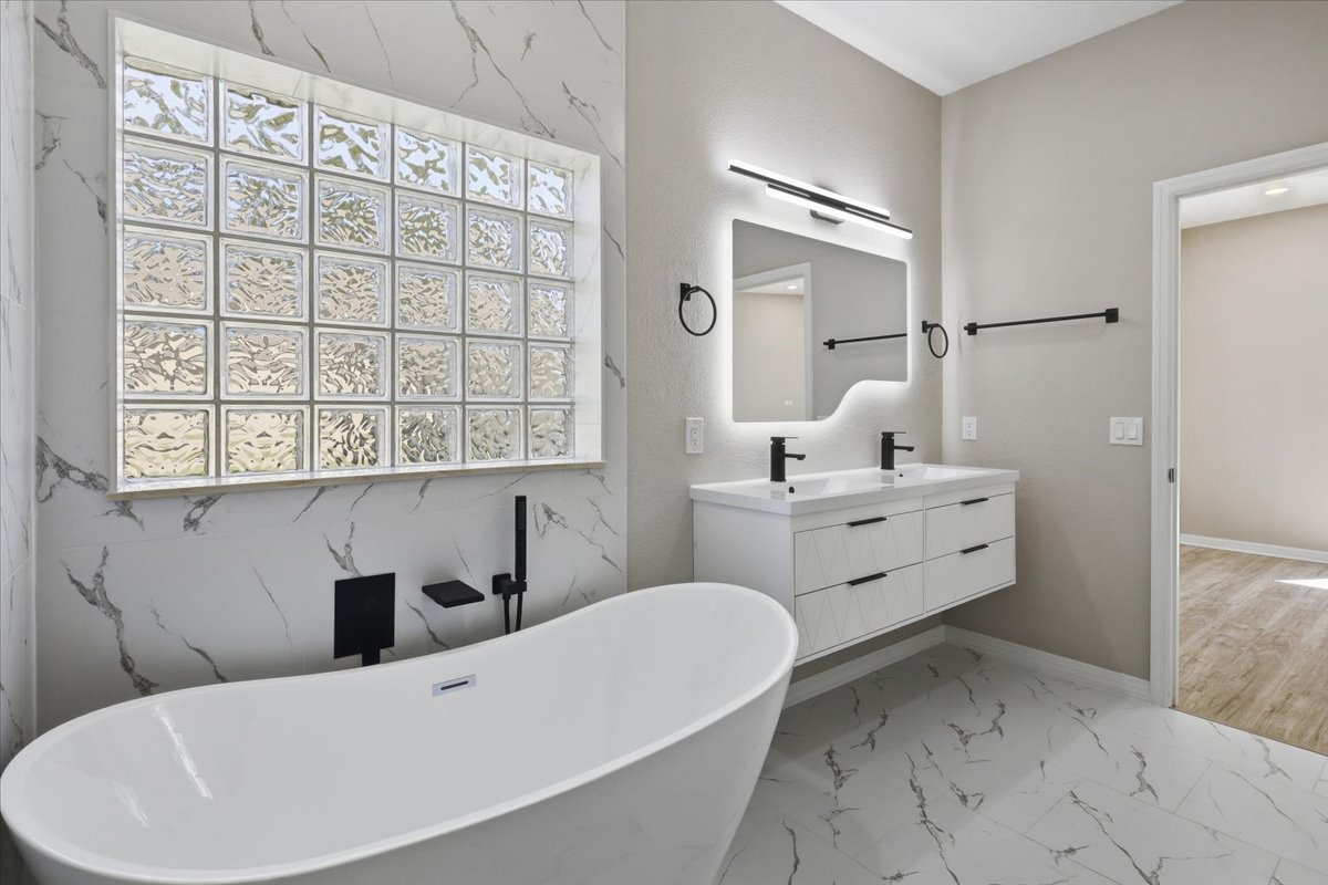 Primary bath with freestanding tub and marble feature wall — The Royal Palms House