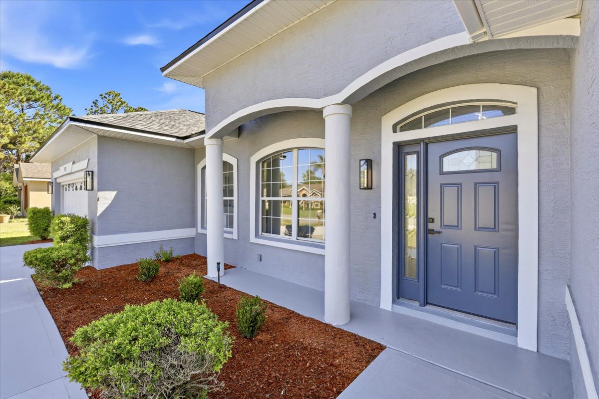 Covered front entry with arched columns and blue door — The Royal Palms House