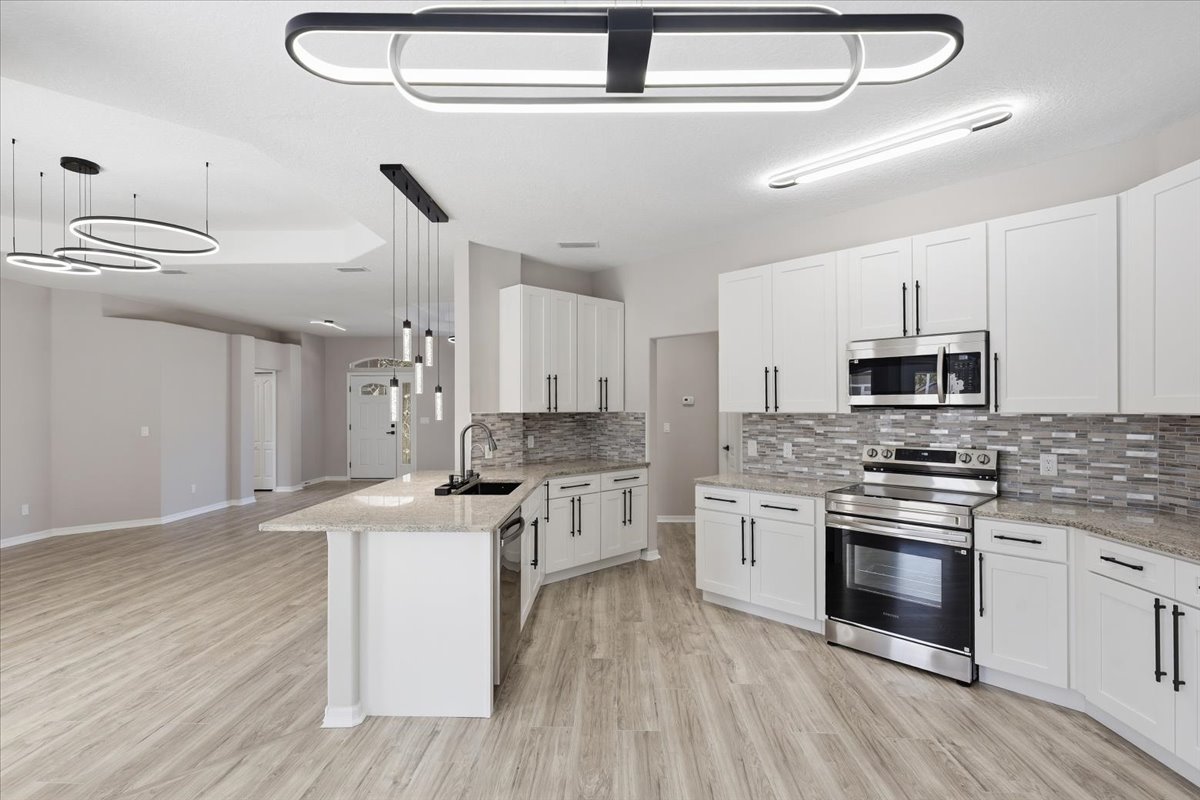 Open-plan kitchen with white cabinetry and modern lighting — The Royal Palms House