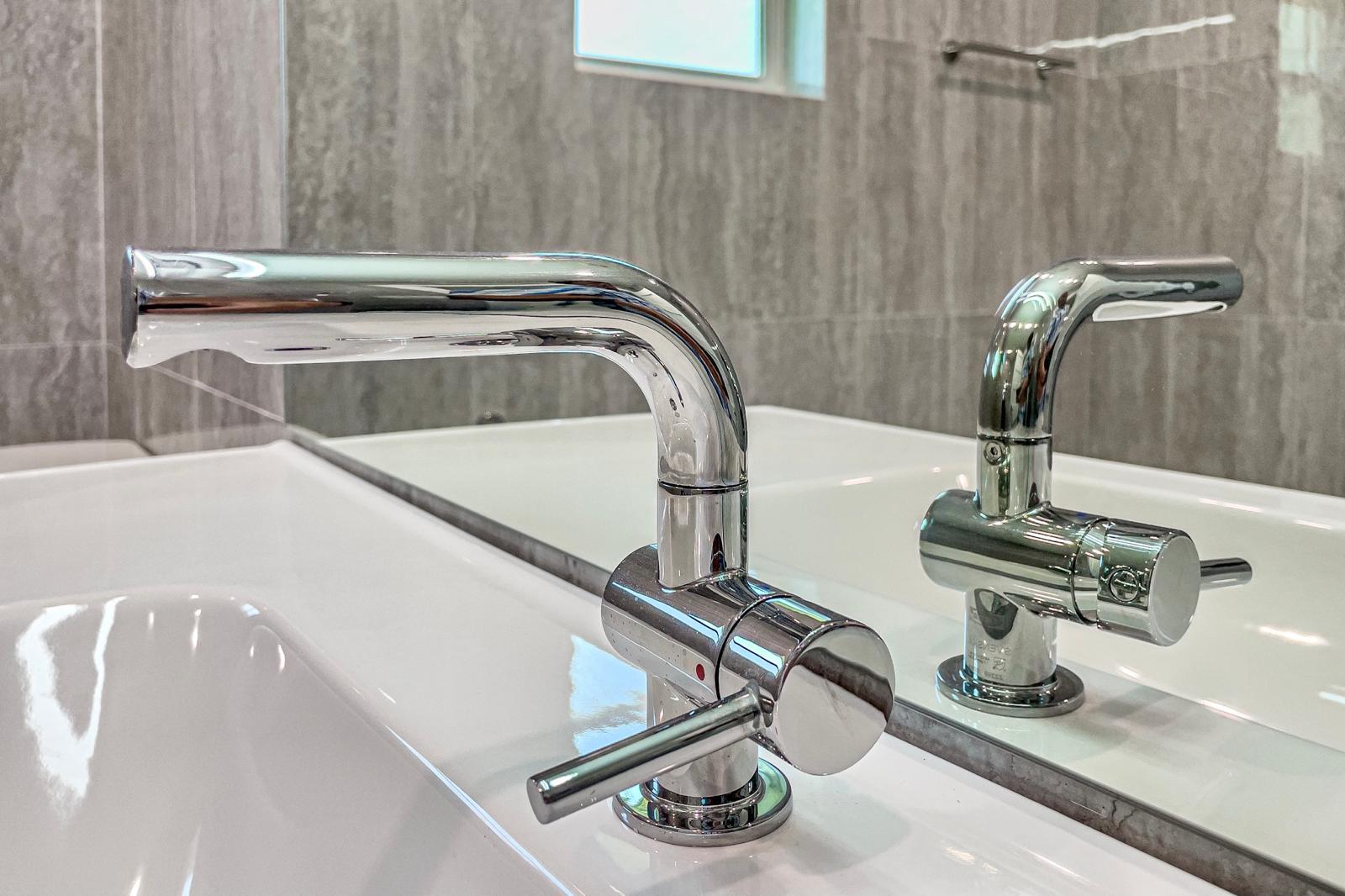 Polished chrome single-handle bath faucet detail — The Travertine Suite, Palm Coast, FL